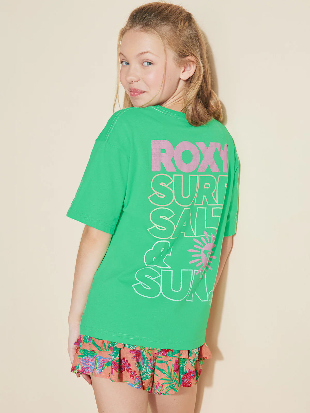 T-Shirt - Roxy vert en coton avec imprimé rose et blanc, style décontracté, porté par une jeune fille vue de dos.