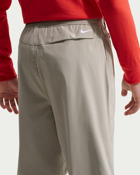 Pantalon ACG - Nike gris beige, style sportif, taille élastiquée et poche arrière à bouton, vue de dos