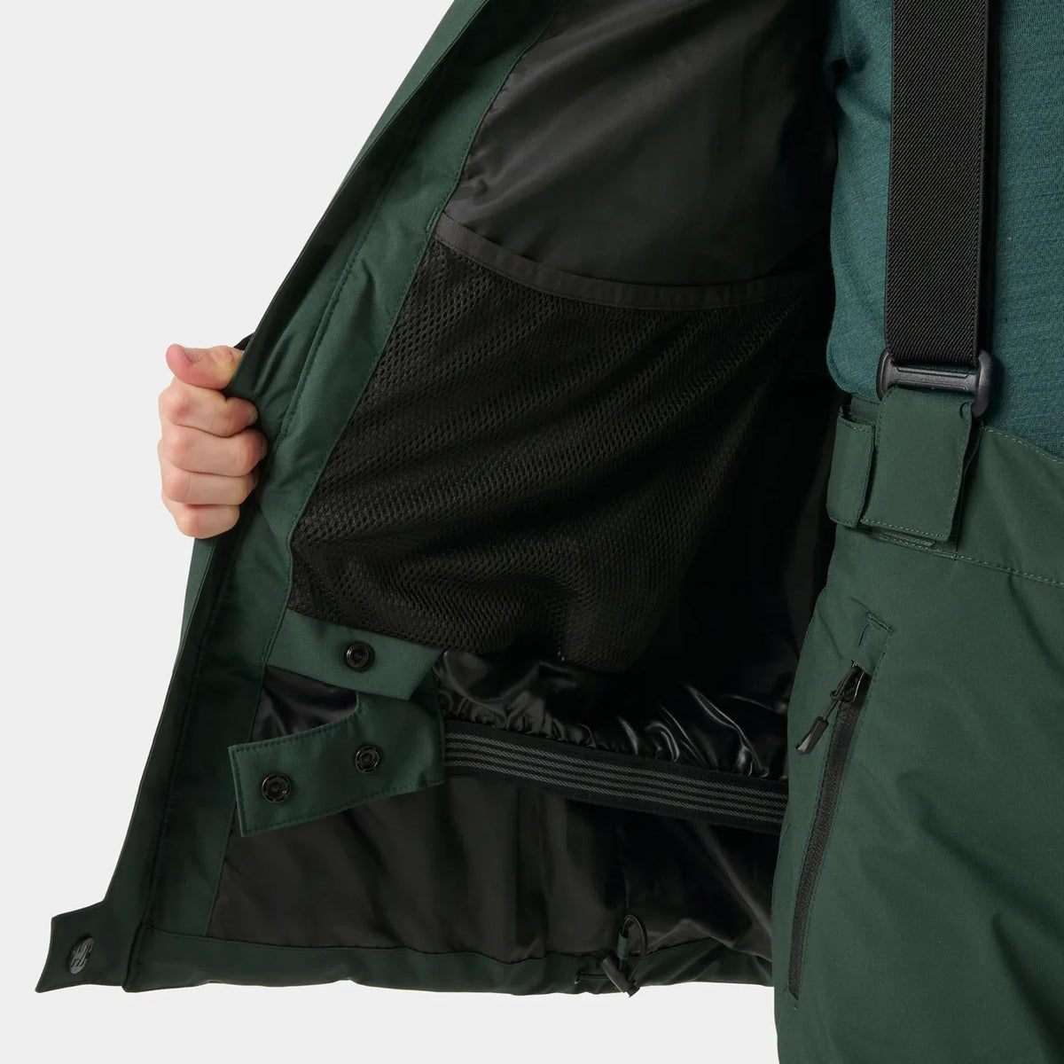 Détail d’une veste vert foncé ouverte, avec doublure en maille noire, boutons-pression et sangle réglable, vue rapprochée