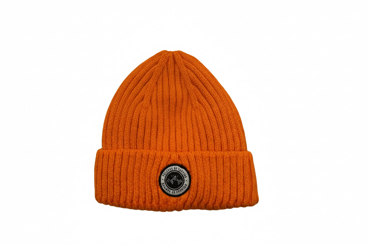 Tuque d'hiver - Peluche & Tartine orange en maille côtelée avec écusson rond, pour enfant, vue de face sur surface en bois clair.