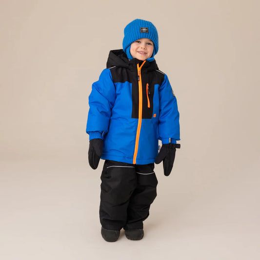 Habit de neige Chris - Nanö bleu royal et noir avec détails orange, ensemble hiver imperméable pour enfant, porté sur mannequin de face, bonnet et moufles assortis.