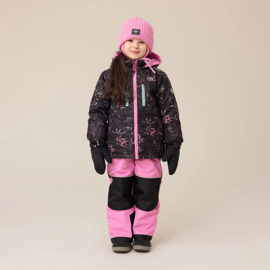 Habit de neige Melody - Nanö pour enfant fille, combinaison noire avec motifs roses et pantalon rose à renforts noirs, portée de face avec bonnet rose et gants noirs.