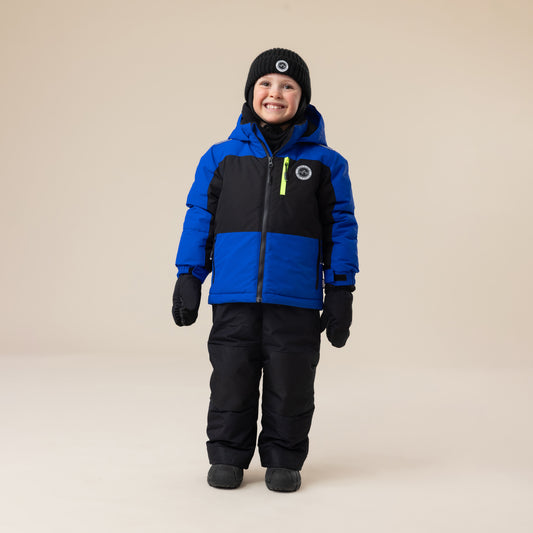 Enfant garçon habillé en Habit de neige - Peluche & Tartine bleu roi et noir avec bonnet noir, gants noirs, pantalon matelassé noir, vue de face.