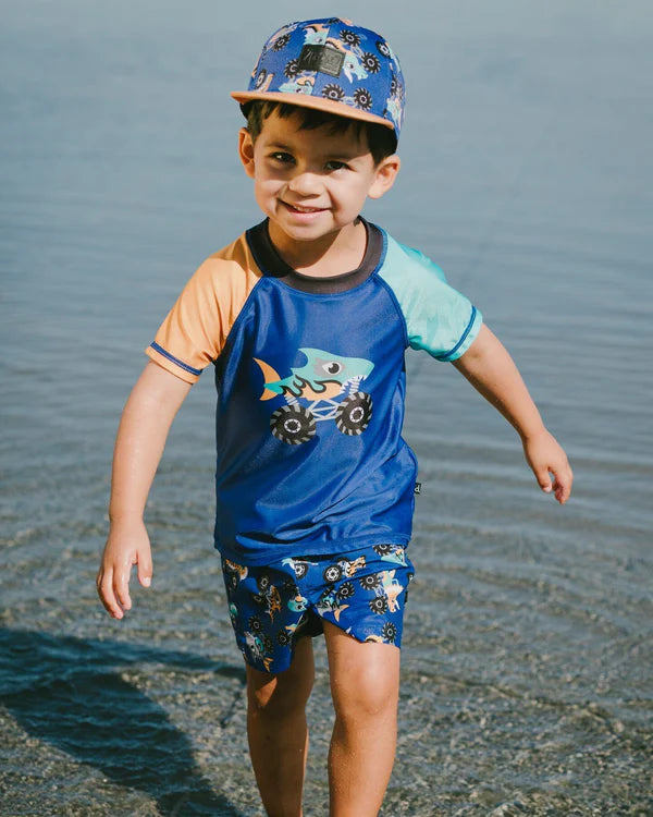 Casquette - Deux Par Deux bleue à imprimé camions monster trucks, portée par garçon, vue de face en extérieur