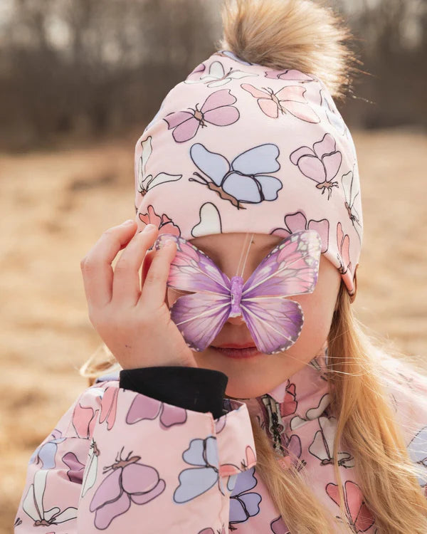 Tuque Mi-Saison - Deux Par Deux rose à motifs papillons bleus et roses avec pompon, pour enfant, vue portée de face sur mannequin fille.