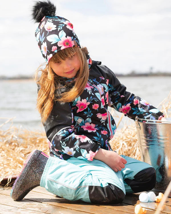 Tuque Mi-Saison - Deux Par Deux noire à fleurs roses et blanches avec pompon, portée par enfant fille, vue de face en extérieur.