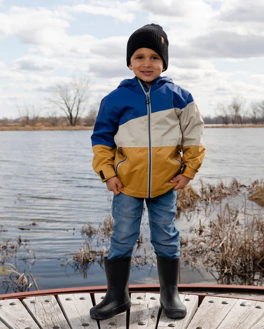 Bottes de pluie - Deux Par Deux noires en caoutchouc naturel portées par garçon, vue de face au bord de l'eau.