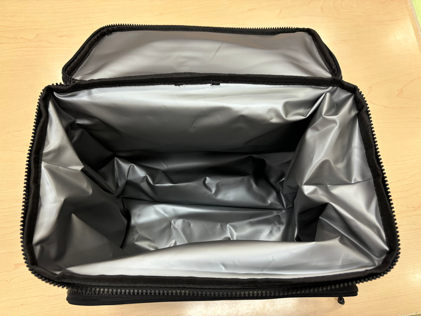 Boite à lunch - Noir avec intérieur isolant argenté, matière souple, pour enfant, vue de dessus ouverte.