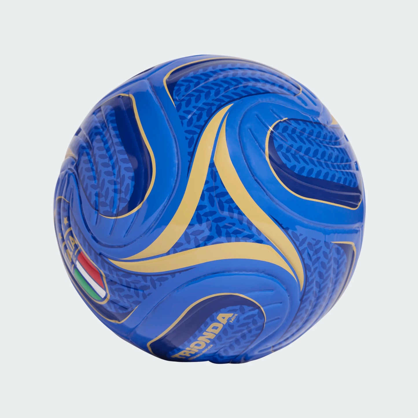 Mini ballon de soccer Trionda Italy Home - Adidas bleu et or avec motifs stylisés, vue rapprochée sur surface texturée.