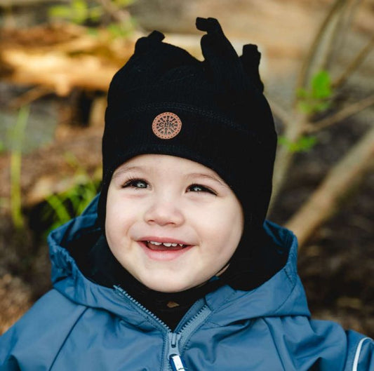 Tuque Mi-Saison - Calikids noire à pointes, portée par un jeune enfant en manteau bleu, vue de face en extérieur