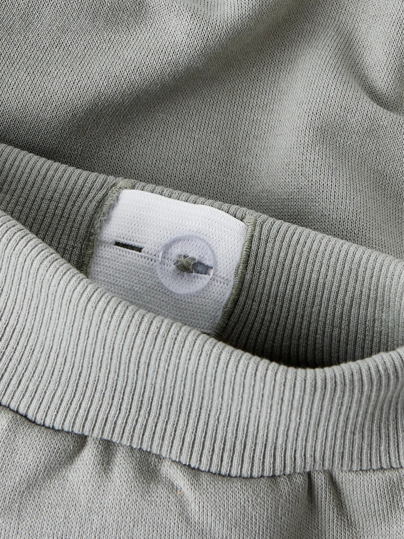 Pantalon - Name It gris clair en coton et polyester, détail de la ceinture élastique avec bouton ajustable, vue rapprochée.