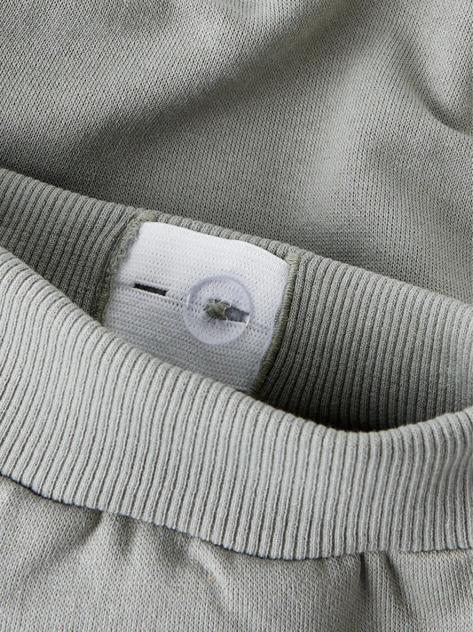 Pantalon - Name It gris clair en coton et polyester, détail de la ceinture élastique avec bouton ajustable, vue rapprochée.