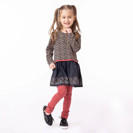 Tunique - Nanö en jersey imprimé marron et jupe noire avec motifs colorés, manches longues froncées, portée par fille, vue de face