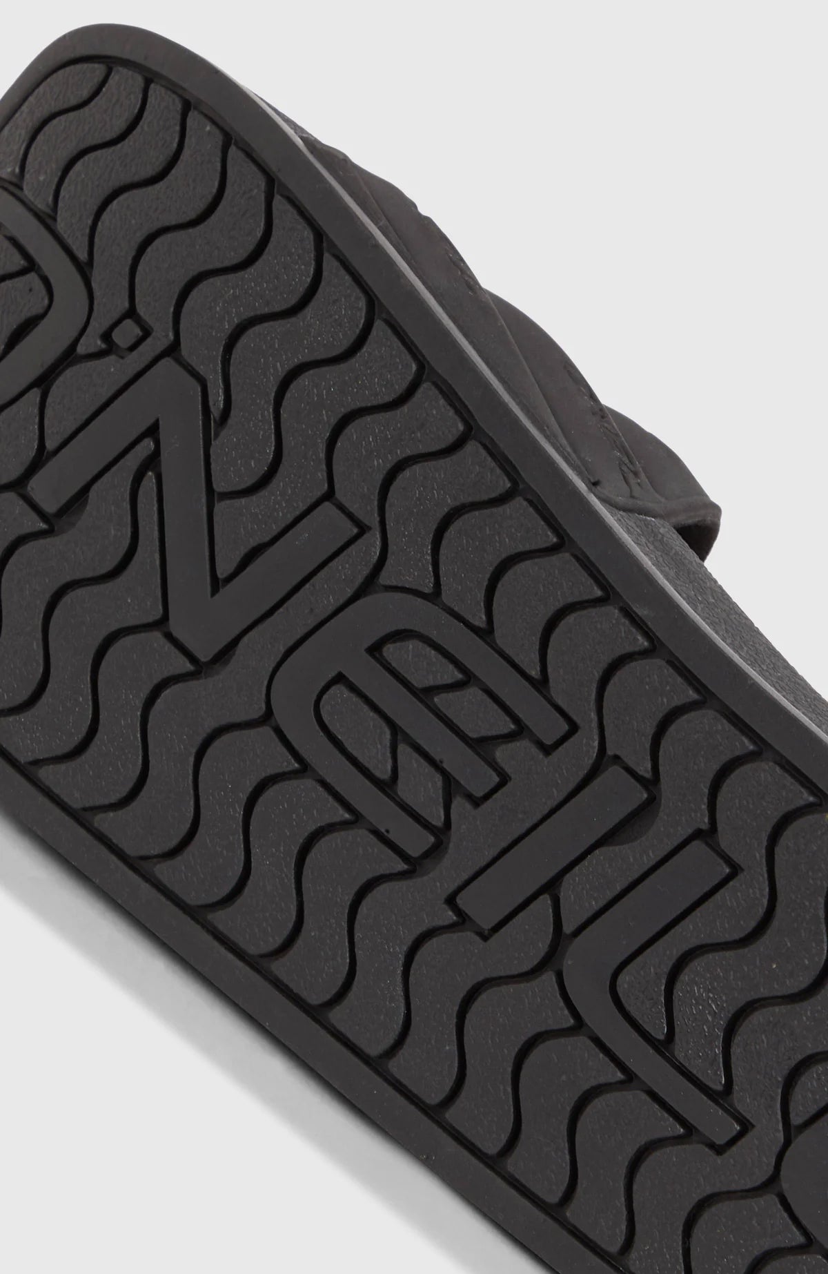 Sandales - THE O'NEILL SLIDES noires avec semelle antidérapante et logo en relief, vue de dessous pour fille.