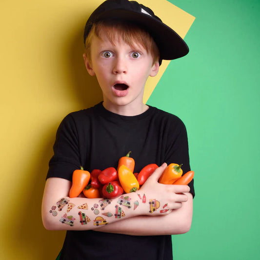 Enfant garçon portant casquette noire, bras tatoué de Pico Tatoo - Les camions de nourriture, tenant des poivrons, vue bras et visage.