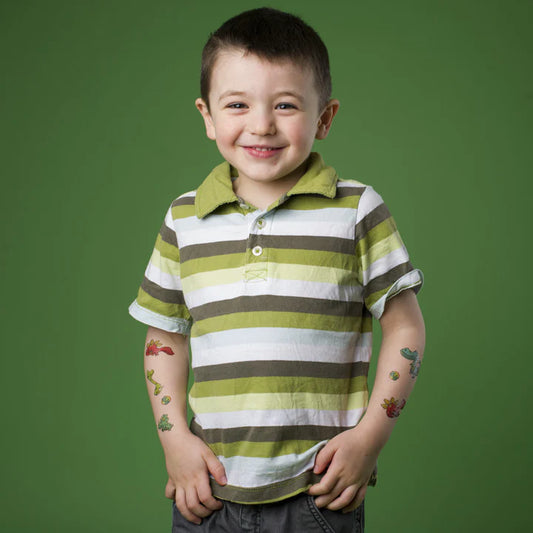 Enfant garçon souriant avec tattoos temporaires colorés dinosaures sur les bras, Polo vert et blanc, vue de face, Pico Tatoo - Les dinos.