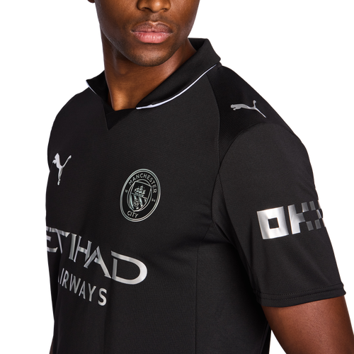 Polo Manchester - Puma noir en polyester avec logo Manchester City et détails argentés, pour garçon, vue de face côté droit.