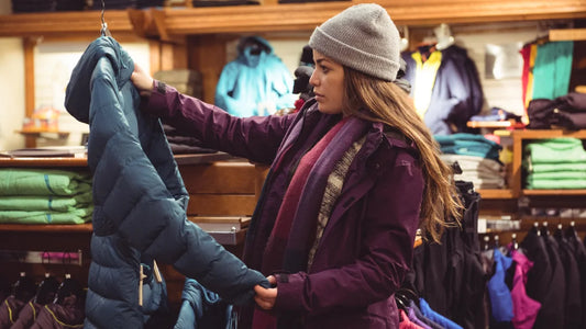 Une femme examine un manteau d'hiver dans un magasin.