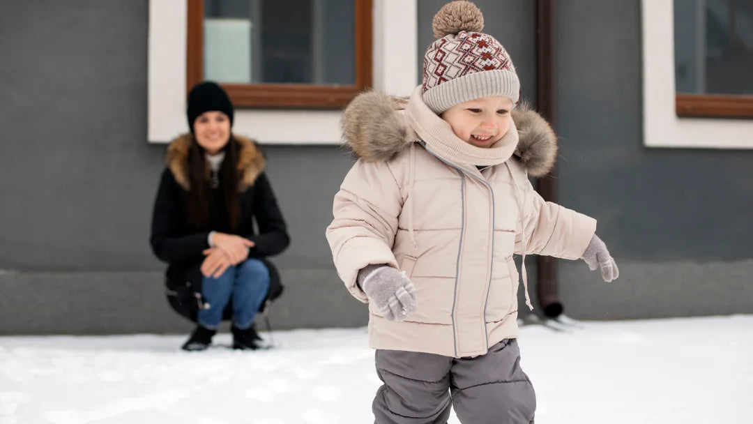 Un petit garçon en manteau d’hiver joue joyeusement dans la neige.