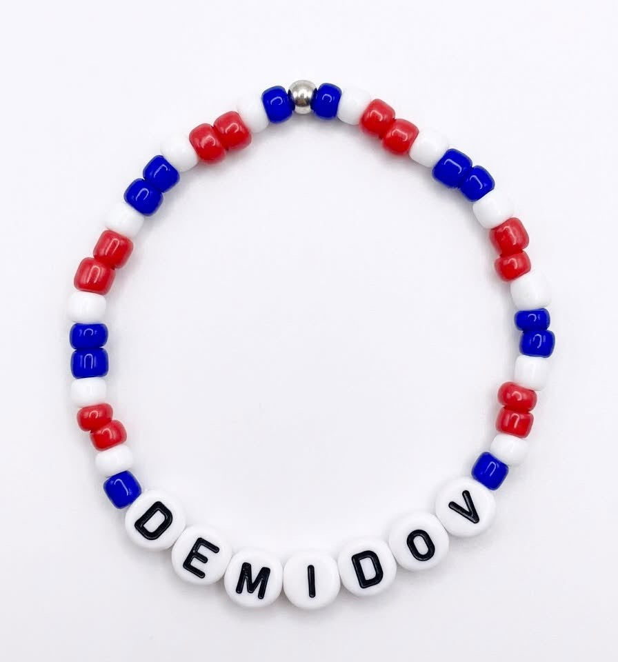 Bracelet - Demidov en perles blanches, rouges et bleues, avec lettres noires, vue de face sur fond clair