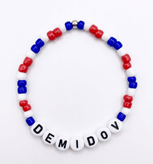 Bracelet - Demidov en perles blanches, rouges et bleues, avec lettres noires, vue de face sur fond clair