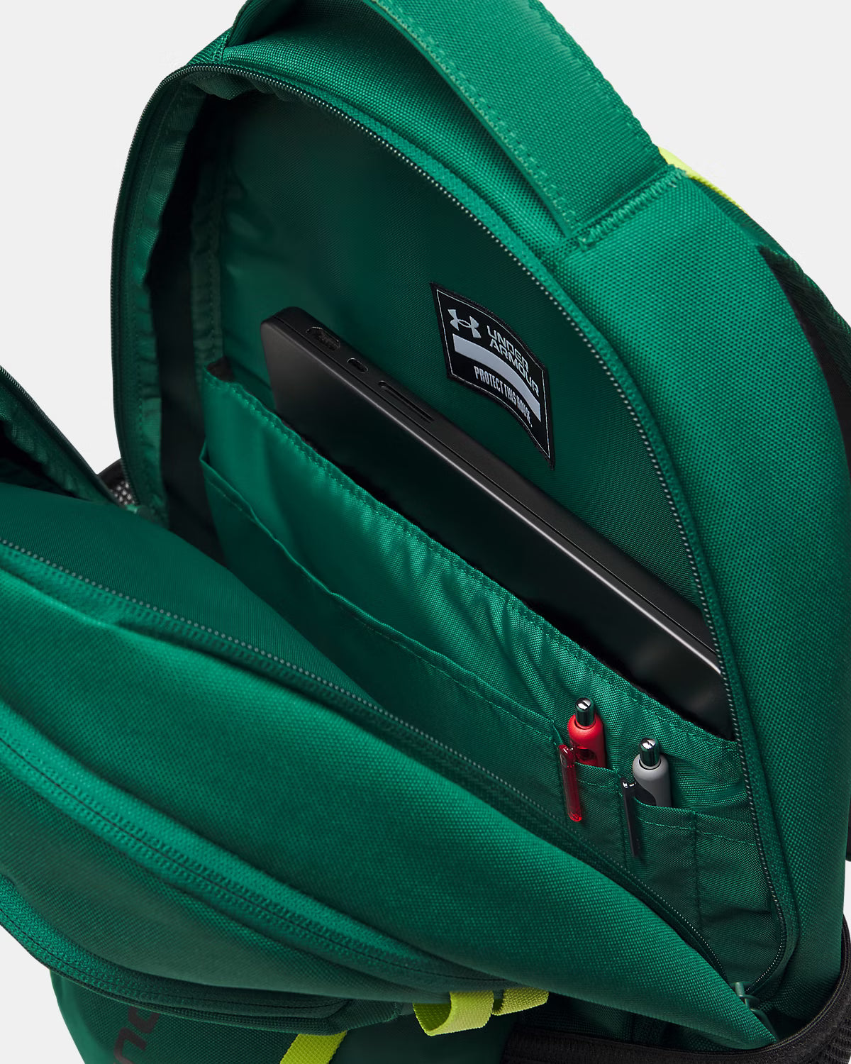 Sac à dos - Under Armour vert en polyester avec compartiment organisé pour ordinateur et stylos, vue intérieure ouverte.