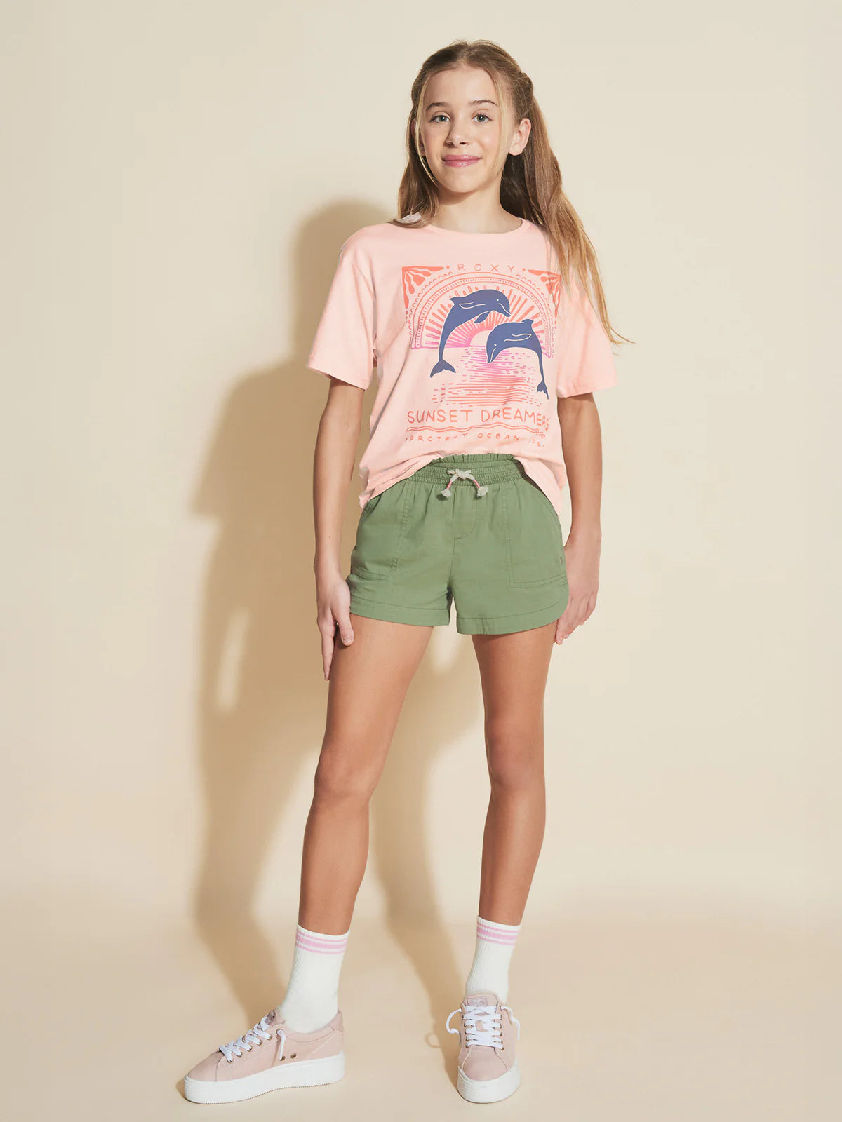 T-Shirt - Roxy rose pâle avec motifs dauphins bleus, pour fille, en coton, porté de face sur mannequin enfant.