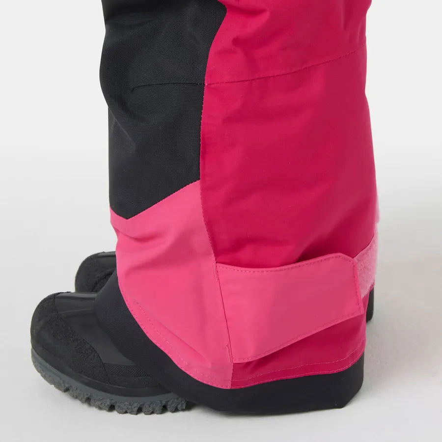 Détail bas de la jambe de la Salopette de neige Rider - Helly Hansen en tissu imperméable rose et noir, vue portée sur enfant.