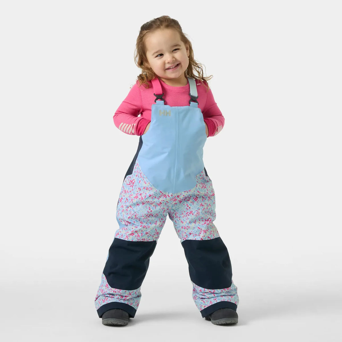 Salopette de neige Rider - Helly Hansen rose et bleu clair à motifs floraux pour fille portée de face sur enfant