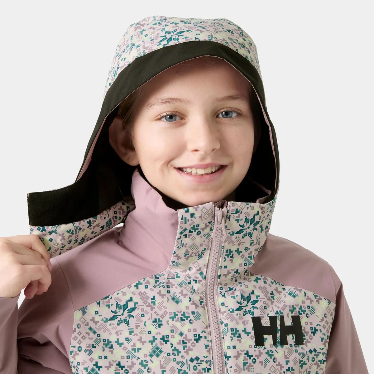 Manteau d'hiver Stellar Jacket 2.0 - Helly Hanse rose pâle et crème à motif géométrique, à capuche, porté par une fille de face