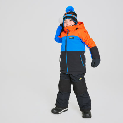 Habit de neige Colibri - Chlorophylle combinant bleu, orange et noir, imperméable, pour enfant garçon, porté debout de face avec bonnet et gants.