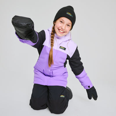 Manteau d'hiver Taïga - Chlorophylle violet clair et noir en tissu isolant, porté par une enfant en vue de face avec bonnet et moufles noires.
