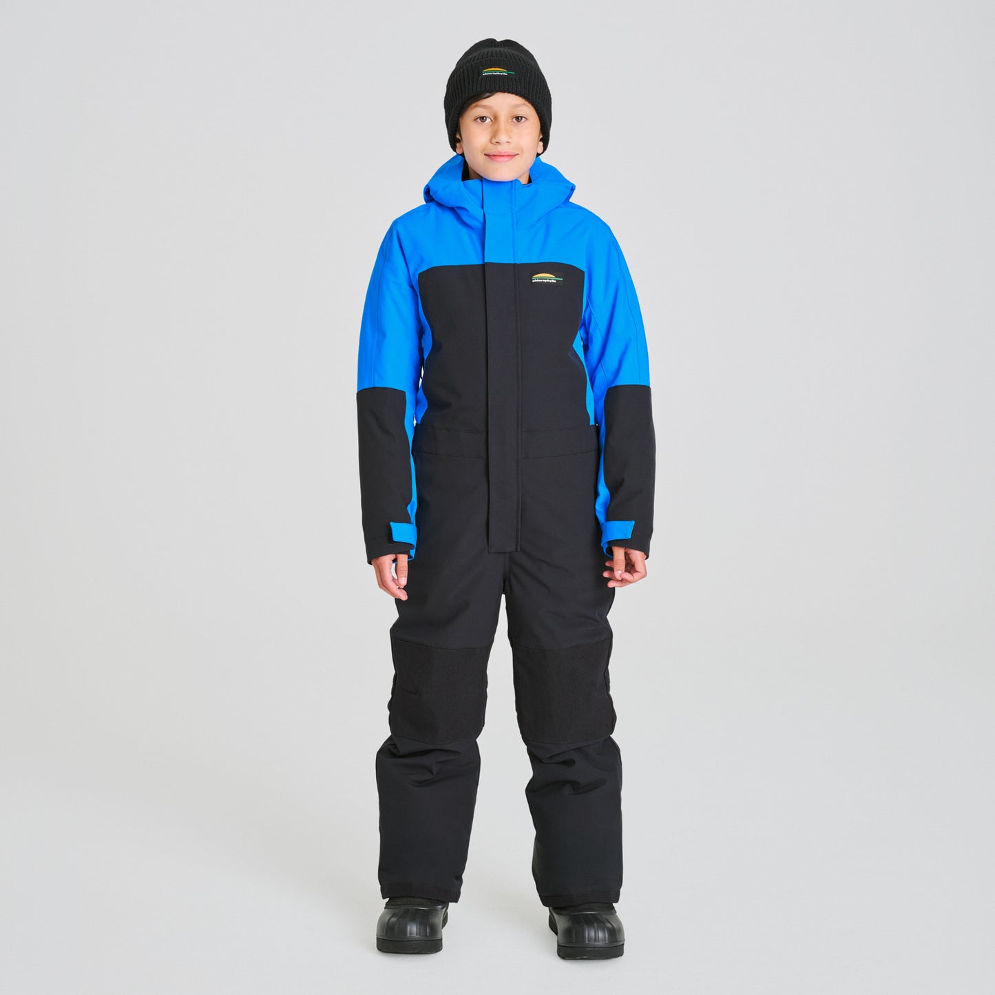 Enfant portant un Habit de neige 1 Pièce - Chlorophylle bleu et noir en tissu technique, combinaison de ski une pièce, vue de face.