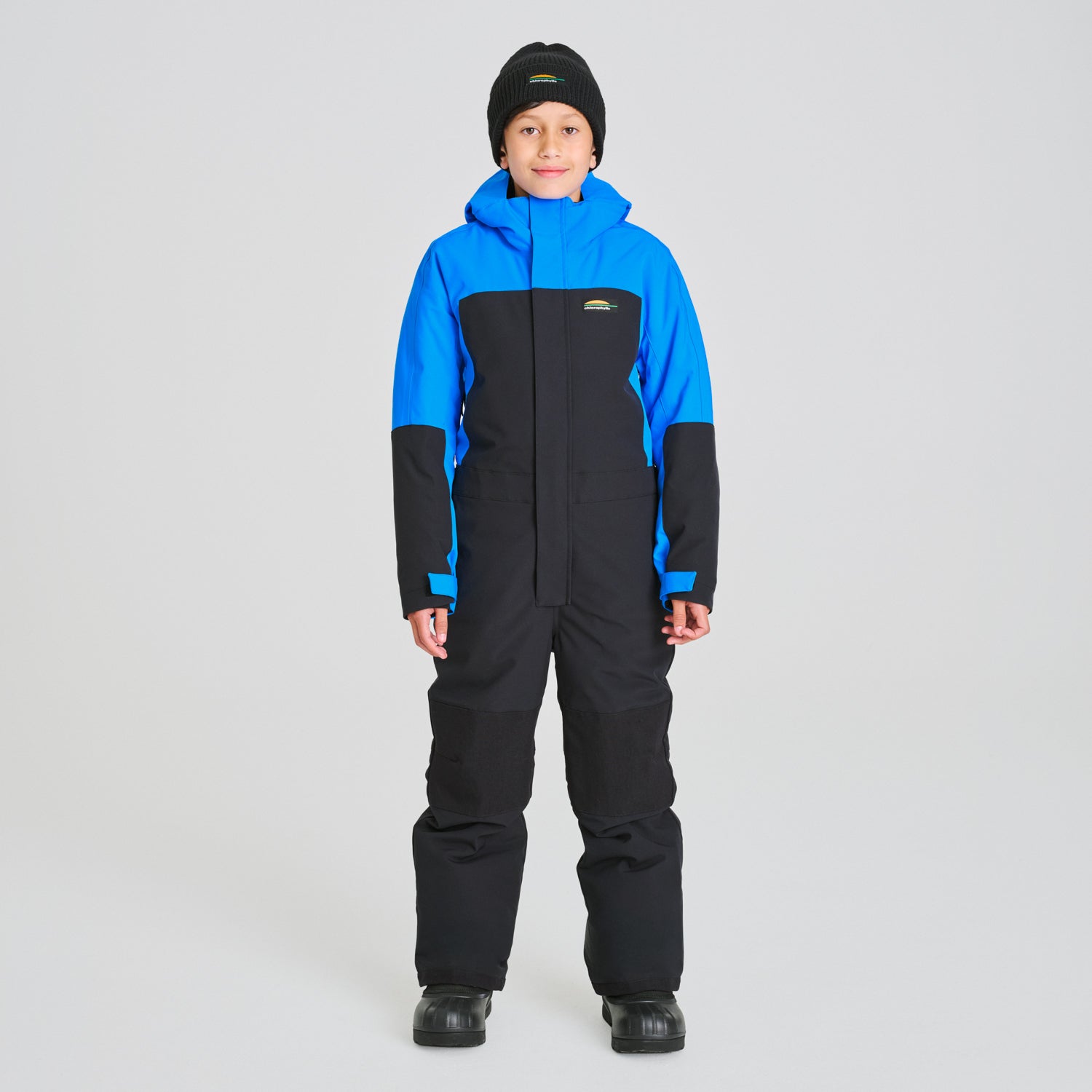 Enfant portant un Habit de neige 1 Pièce - Chlorophylle bleu et noir en tissu technique, combinaison de ski une pièce, vue de face.