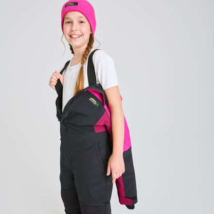 Habit de neige 1 Pièce - Chlorophylle noir et rose porté par une enfant, vue de profil, en tissu imperméable avec bretelles réglables, bonnet rose.