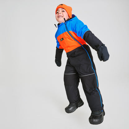 Habit de neige 1 pièce - Chlorophylle, combinaison enfant multicolore bleu, orange et noir, en tissu imperméable, vue portée trois quarts avec bonnet orange et gants noirs.