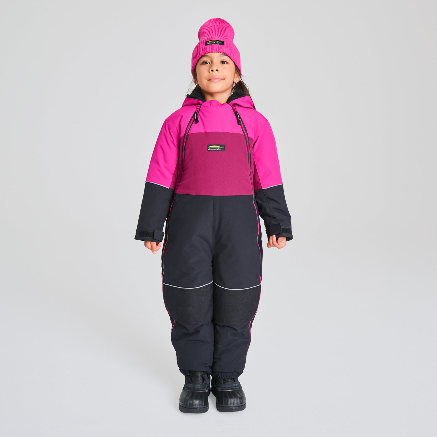Habit de neige 1 pièce - Chlorophylle rose fuchsia, prune et noir, en tissu imperméable, pour enfant, vue de face porté sur mannequin.