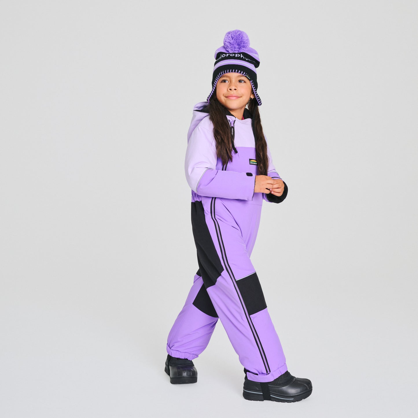 Habit de neige 1 pièce - Chlorophylle violet et noir en matière isolante, style combinaison intégrale, porté par enfant vue de trois quarts.