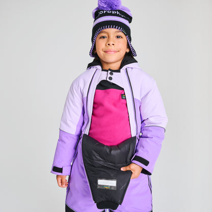 Enfant portant un Habit de neige 1 pièce - Chlorophylle lilas et noir, coupe longue avec détails isolants, vue de face sur mannequin garçon.