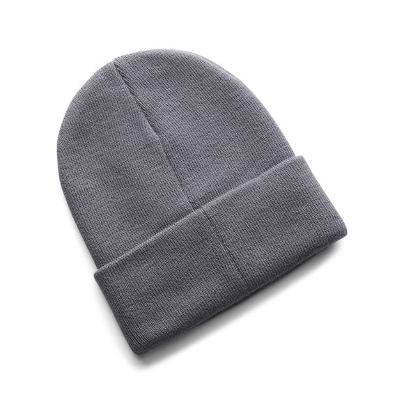 Tuque d'hiver - Under Armour en tricot gris, style classique avec revers, vue de dessus sur fond blanc.
