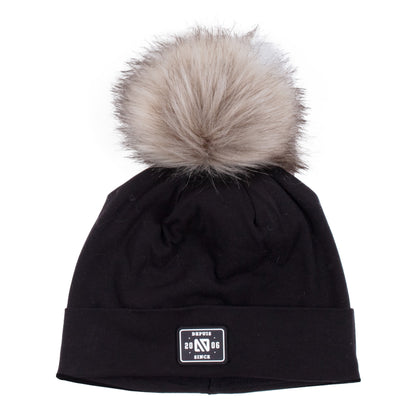 Tuque Mi-Saison noire avec pompon en fausse fourrure beige, en tissu doux, vue de face adaptée pour enfant.