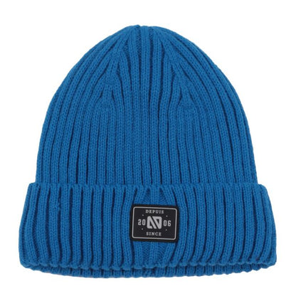 Tuque d'hiver - Nanö en tricot bleu à côtes avec revers large et écusson noir, vue de face.