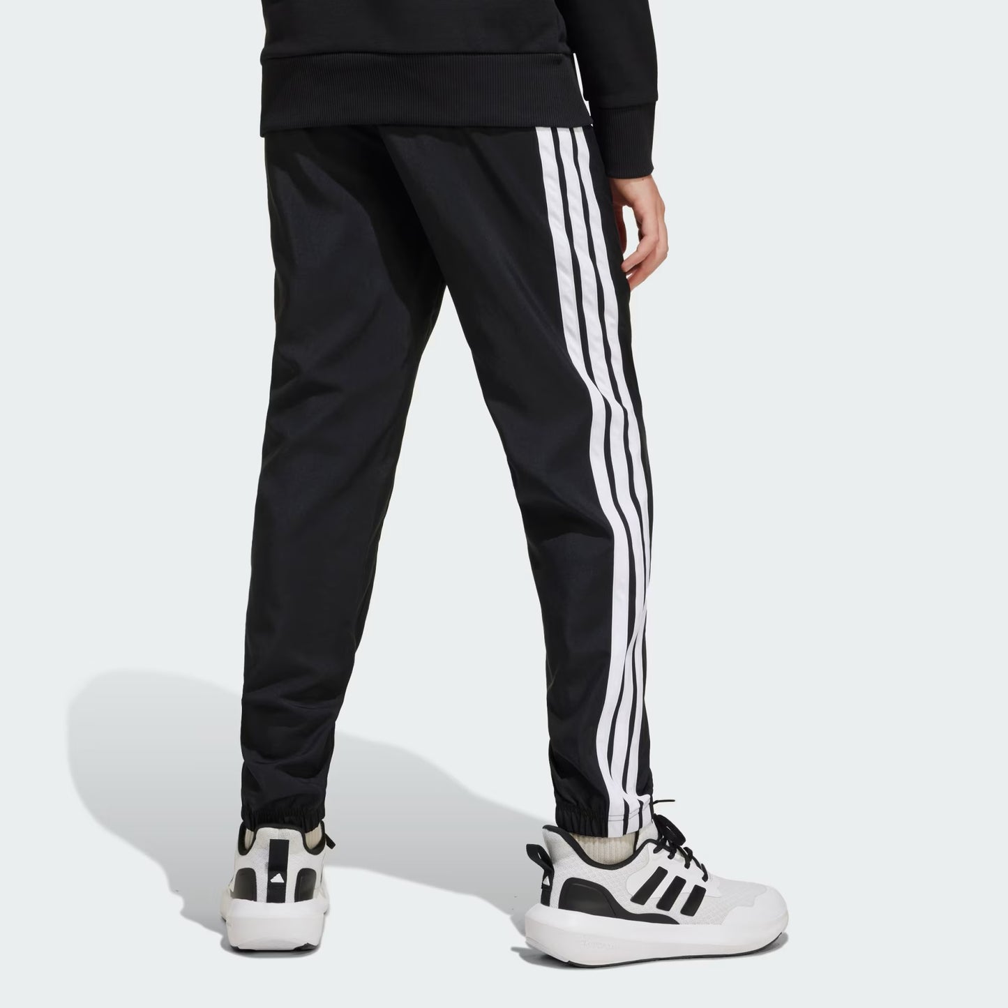 Pantalon - Adidas noir avec bandes blanches latérales, style sportif, en tissu respirant, porté par enfant, vue de dos.