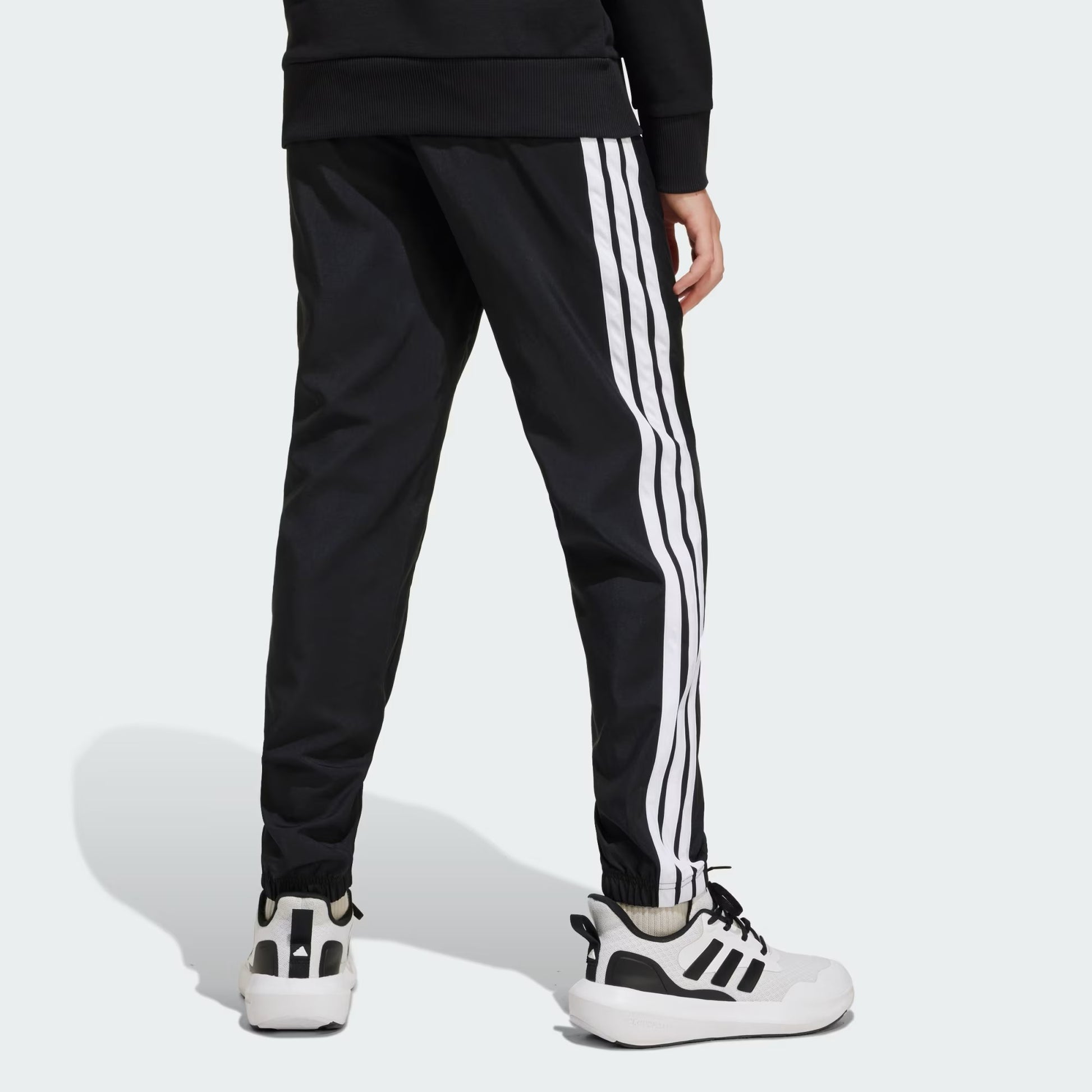 Pantalon - Adidas noir avec bandes blanches latérales, style sportif, en tissu respirant, porté par enfant, vue de dos.