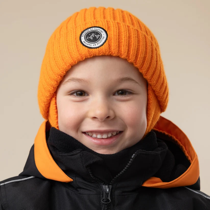 Tuque d'hiver - Peluche & Tartine orange en maille portée par un enfant vue de face avec manteau noir et orange
