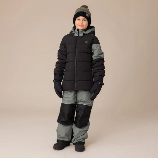Habit de neige Antonin - Nanö porté par enfant, combinaison hiver noire et grise avec gants, vue de face sur fond neutre.
