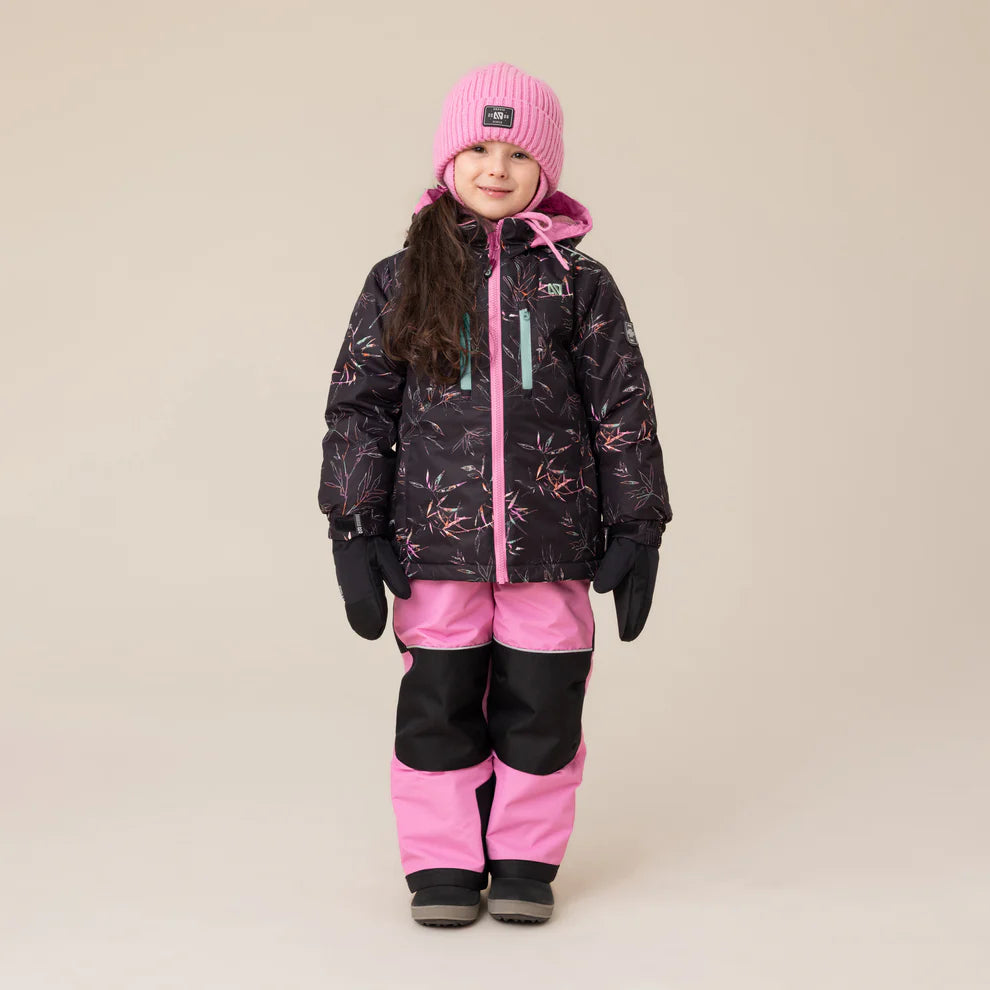 Habit de neige Melody - Nanö pour enfant fille, combinaison noire avec motifs roses et pantalon rose à renforts noirs, portée de face avec bonnet rose et gants noirs.