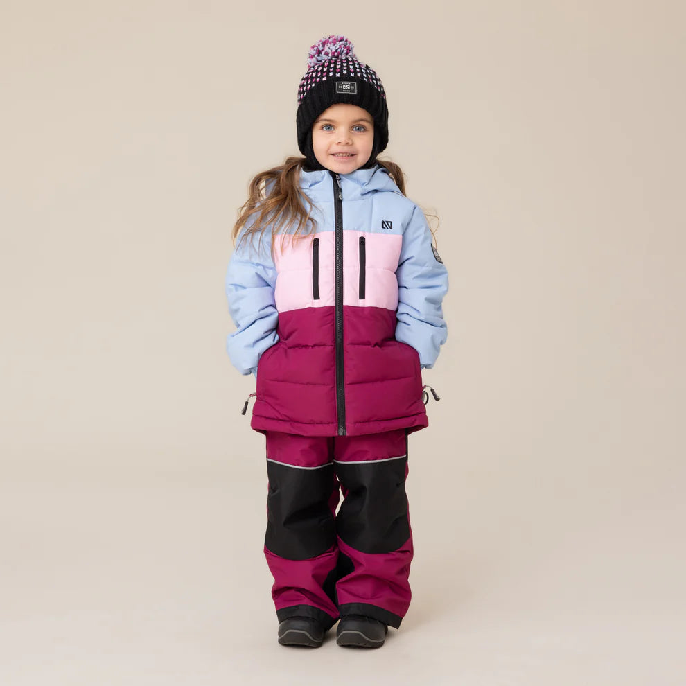 Habit de neige Anabel - Nanö tricolore bleu clair, rose et bordeaux pour enfant, en tissu mat, vue de face porté par une fillette avec bonnet noir à pompon.