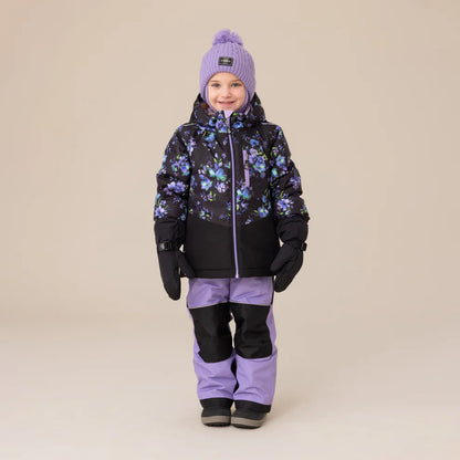 Habit de neige Lara - Nanö pour enfant fille, combinaison noire à imprimé floral violet et bleu avec pantalon lilas, vue de face portée sur mannequin enfant.