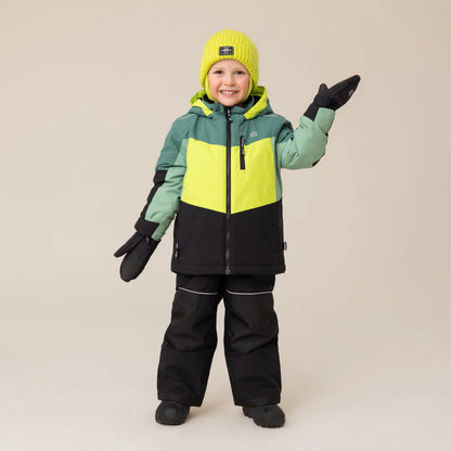 Enfant portant un Habite de neige performance vert - Nanö, veste en vert clair, vert foncé et noir, bonnet jaune, vue de face avec gants noirs.